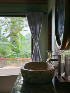 a bathroom with a stone bowl sink in front of a window at Lira House by Yukaya Escape in Tegalalang