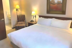 a bedroom with a large white bed and a chair at Quality Inn West Lafayette - University Area in Lafayette +6 photos