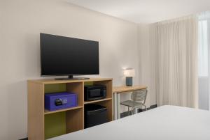a bedroom with a tv and a desk with a chair at Spark By Hilton Seattle Airport in Seattle