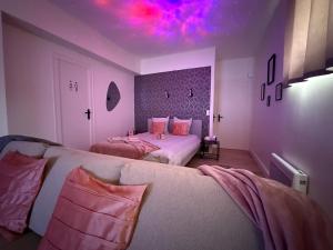a bedroom with two beds and a pink ceiling at Le nid des étoiles - Tram & Centre in Dijon