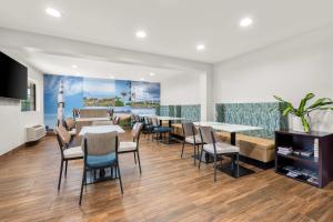 a restaurant with tables and chairs and a painting on the wall at Clarion Pointe Athens I-65 in Athens