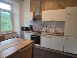 a kitchen with white cabinets and a wooden table at Ferienhaus im Moseltal in Bruttig-Fankel