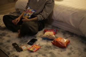 a woman sitting on a bed with food and snacks at Behomestay in Hai Phong