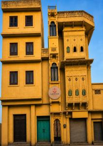 a tall yellow building with green doors at Lighthouse Hostel in Udaipur