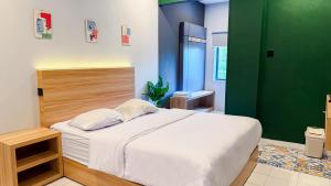 a bedroom with a white bed and a green wall at HUBS Hostel Yogyakarta in Yogyakarta
