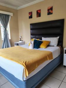 a bedroom with a large bed with yellow and blue pillows at Monono Guesthouse in Bloemfontein