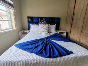 a blue and white bed with a blue blanket on it at Monono Guesthouse in Bloemfontein