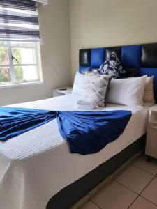 a large bed with blue and white pillows on it at Monono Guesthouse in Bloemfontein