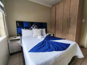 a bedroom with a bed with a blue blanket on it at Monono Guesthouse in Bloemfontein