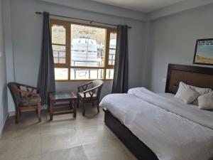 a bedroom with a bed and two chairs and a window at Hotel Sidharth Tabo in Tabo