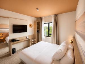 a hotel room with a bed and a television at The Originals Boutique, Osmo Hôtel, Rennes Sud Chantepie in Chantepie