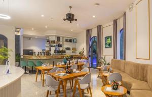 a restaurant with tables and chairs and a couch at Dalat Hotel & Villa by Pham Gia in Xuan An