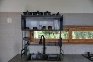 a shelf with pots and pans above a kitchen sink at Kampuak Cottages in Nusa Penida