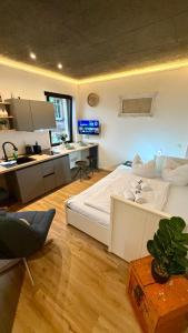 a bedroom with a large white bed and a kitchen at Design Apartment Arndt in Neustadt an der Weinstrasse in Neustadt an der Weinstraße