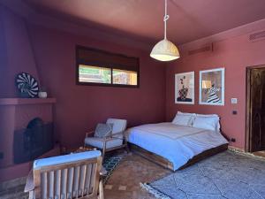 a bedroom with a bed and a chair and a fireplace at villa lalla Ourika & heated pool in Aghbalou