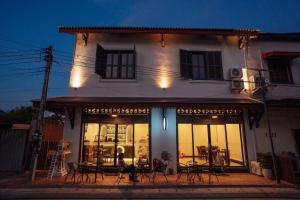 a building with tables and chairs in front of it at Nam Phou Hostel in Thakhek