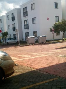 a white building with a parking lot in front of it at Modern apartment for work and rest in Kiambu