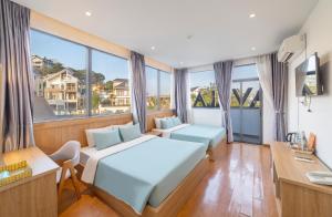 a bedroom with a bed and a desk and windows at Dalat Hotel & Villa by Pham Gia in Xuan An