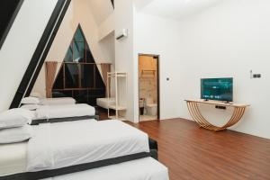 a room with four beds and a television in it at Acasa Cottage by Samsara in Cipaok
