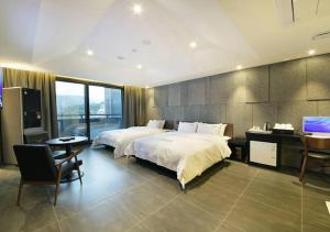 a bedroom with two beds and a desk and a television at Anyang Boutique Hotel AMA in Anyang +1 photo