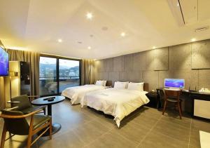 a hotel room with two beds and a desk and a computer at Anyang Boutique Hotel AMA in Anyang