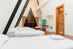 a room with four white beds and a window at Acasa Cottage by Samsara in Cipaok