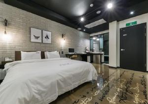 a bedroom with a large white bed and a desk at Anyang Boutique Hotel AMA in Anyang