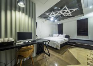 a bedroom with a bed and a desk with a computer at Anyang Boutique Hotel AMA in Anyang