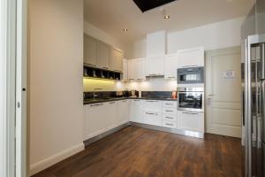 a kitchen with white cabinets and a wooden floor at Apartments Kozmo Residences Budapest in Budapest +89 photos