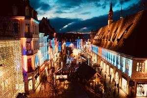 a city street with lit up buildings at night at Loft Sous Pref in Montbéliard +6 photos