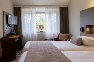 a hotel room with a bed and a desk and a window at 50|50 Hotel Belmont in Ede +37 photos