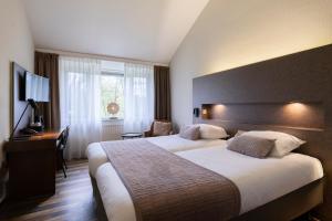 a hotel room with two beds and a desk at 50|50 Hotel Belmont in Ede