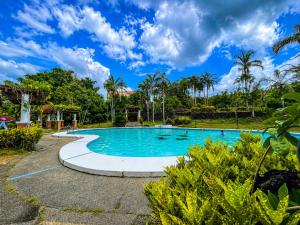 a swimming pool at a resort with palm trees at Graceland Resort Tayabas Quezon in Tayabas