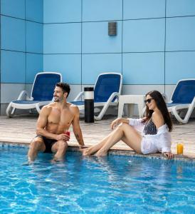 a man and a woman sitting in a swimming pool at Copthorne Hotel Sharjah in Sharjah +208 photos