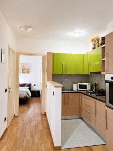 a kitchen with green cabinets and a bed in a room at Apartment near Lake Como -300m to station -AC in Valmadrera