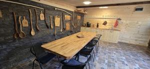 a wooden table and chairs in a room with utensils at Farma pod Skalkou in Heľpa