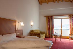a hotel room with a bed and a large window at Alpenhotel Ramsauerhof in Ramsau im Zillertal +28 photos
