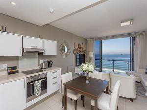 a kitchen and dining room with a table and a view of the ocean at Infinity Self Catering Apartments in Bloubergstrand