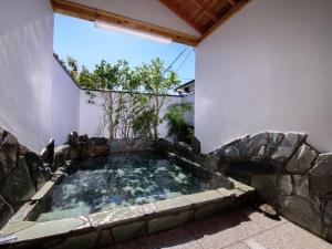 a hot tub in the corner of a building at Koto no Kashin in Yufu
