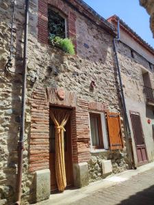 an old stone building with a door with a ribbon on it at Al clouc in CampÃ´me