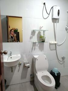 a woman taking a picture of a bathroom with a toilet and sink at Room 5 in Siquijor +19 photos