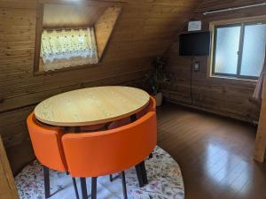 a dining room with a table and orange chairs at のんびれっじ つくし棟 in Anazawa