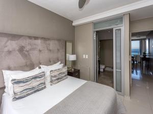 a bedroom with a large bed with white sheets and pillows at Infinity Self Catering Apartments in Bloubergstrand +24 photos