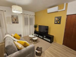 a living room with a couch and a flat screen tv at Le Nid De Mouroux - Disney 20 min - Clim & Parking in Mouroux