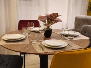 a wooden table with plates and wine glasses on it at Le Nid De Mouroux - Disney 20 min - Clim & Parking in Mouroux