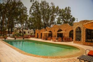 a swimming pool in front of a brick building at Maison d'hôtes Villa Latifa Essaouira in Essaouira