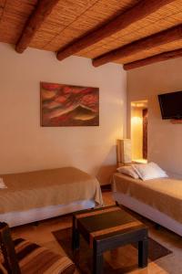 a hotel room with two beds and a tv at Al Sereno Hotel Spa in Tilcara