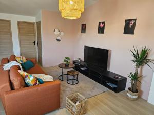 a living room with a couch and a flat screen tv at L'écrin De Mouroux - Disney 20 min - Clim & Parking in Mouroux