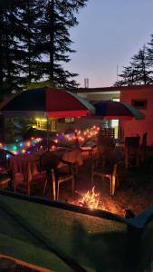 a group of tables and umbrellas in front of a fire at Ananta Valley Home's in Kulu