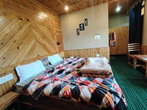 a bed in a room with a wooden wall at Ananta Valley Home's in Kulu